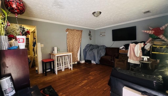 living area with a textured ceiling, ornamental molding, wood finished floors, and visible vents