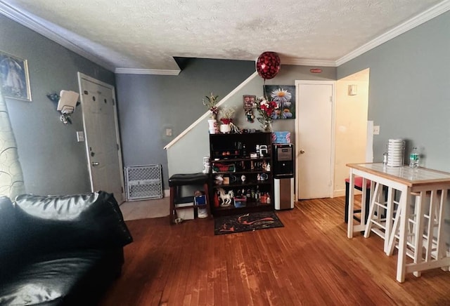 living area with a textured ceiling, ornamental molding, and wood finished floors