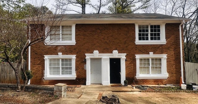 colonial home featuring brick siding and fence