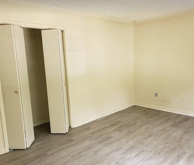 unfurnished bedroom with baseboards, a closet, ornamental molding, and wood finished floors