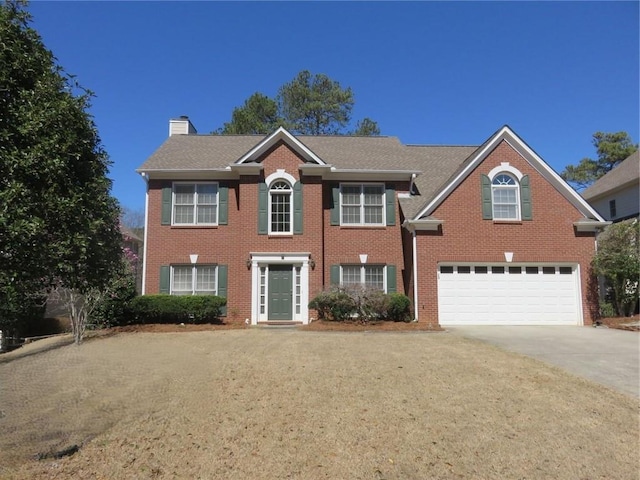 colonial home with brick siding, a chimney, concrete driveway, and an attached garage