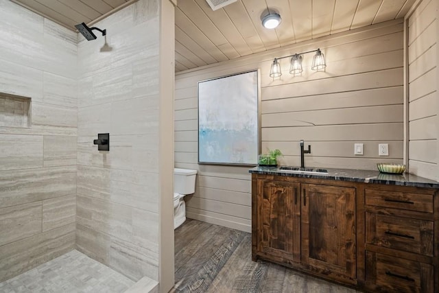 bathroom with toilet, wooden ceiling, a tile shower, vanity, and hardwood / wood-style floors