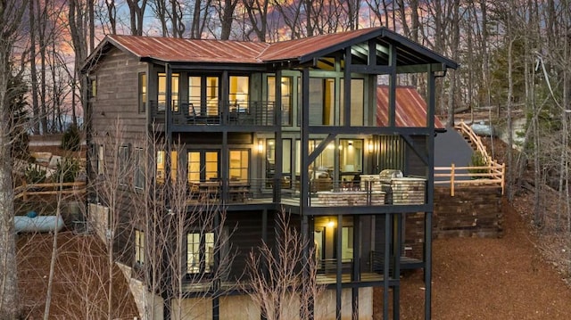 back house at dusk featuring a balcony