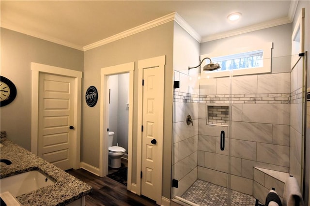 full bathroom featuring crown molding, toilet, a stall shower, wood finished floors, and a sink