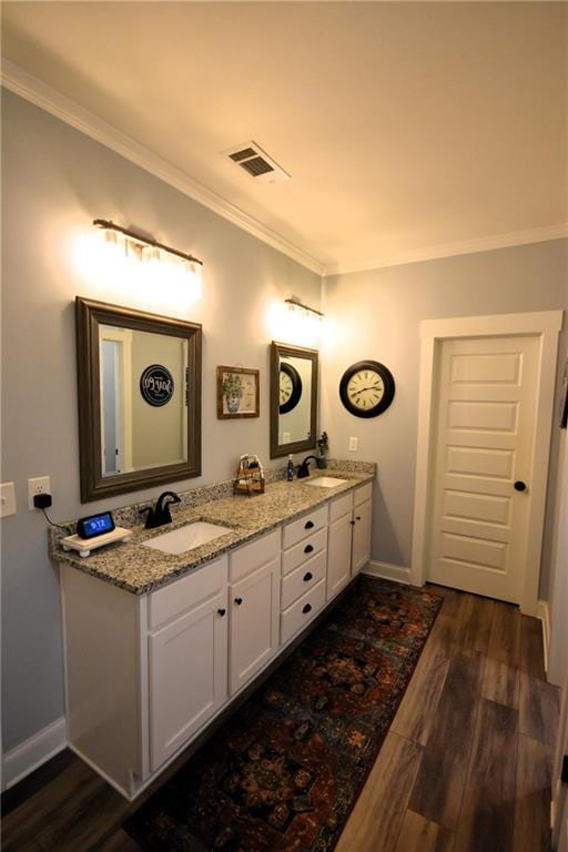 full bathroom with visible vents, a sink, wood finished floors, crown molding, and double vanity