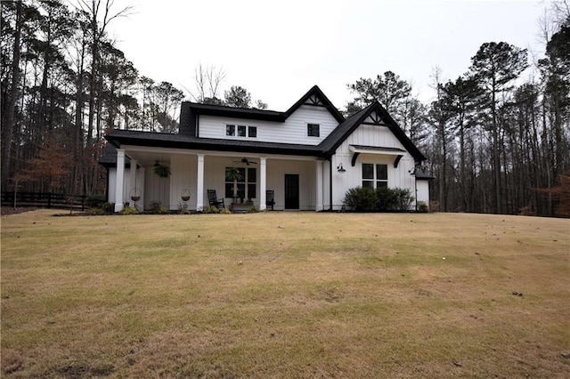 modern farmhouse with board and batten siding, a front lawn, fence, a porch, and a ceiling fan