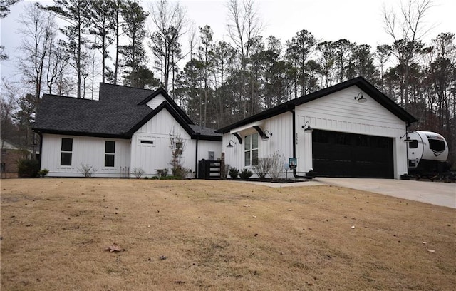 modern farmhouse with a front lawn, board and batten siding, concrete driveway, an attached garage, and roof with shingles