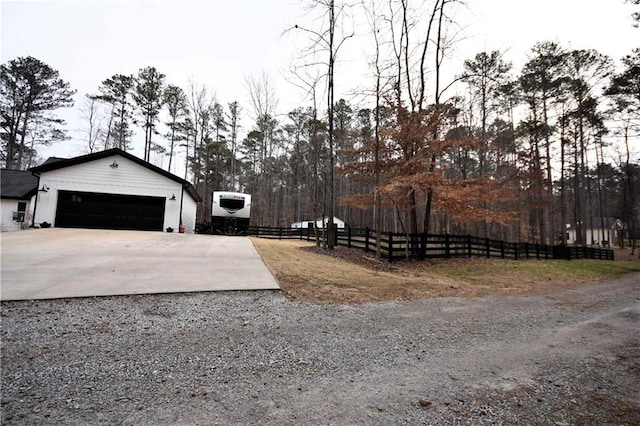 view of yard with an outbuilding, driveway, and fence