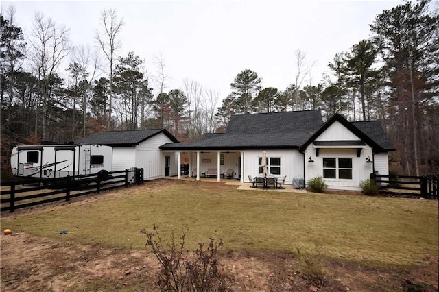 rear view of house featuring a patio, a yard, fence, and roof with shingles