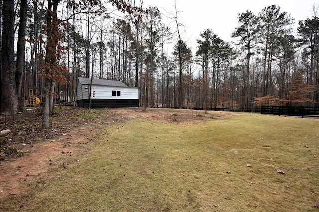 view of yard with an outdoor structure, fence, and dirt driveway