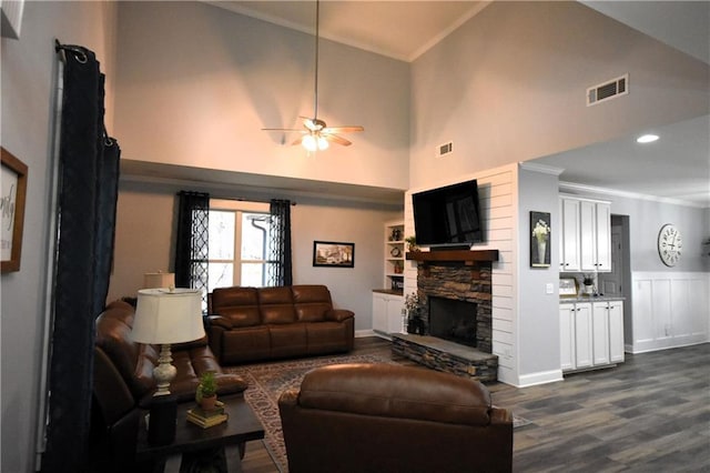 living area featuring a stone fireplace, crown molding, visible vents, and ceiling fan