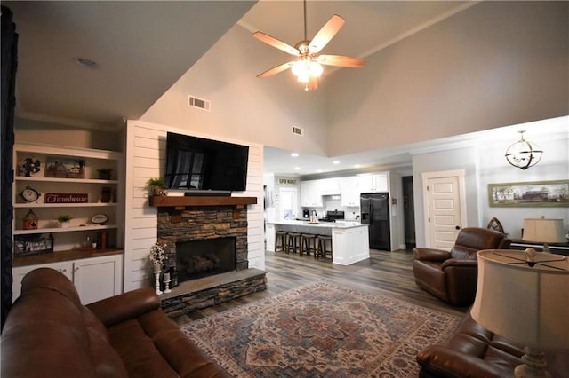 living area with visible vents, dark wood-style floors, a fireplace, crown molding, and ceiling fan