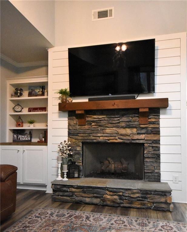 interior details with visible vents, ornamental molding, a fireplace, and wood finished floors