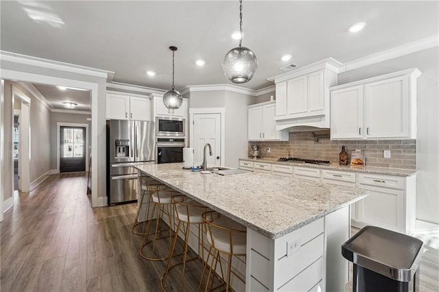 kitchen featuring white cabinets, decorative backsplash, a kitchen island with sink, and appliances with stainless steel finishes