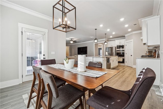 dining room featuring ceiling fan with notable chandelier, light hardwood / wood-style floors, and crown molding