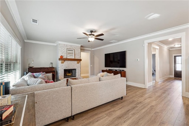 living room with light hardwood / wood-style floors, a fireplace, ornamental molding, and plenty of natural light