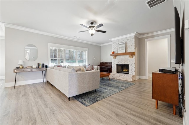 living room with ceiling fan, light hardwood / wood-style flooring, a brick fireplace, and crown molding