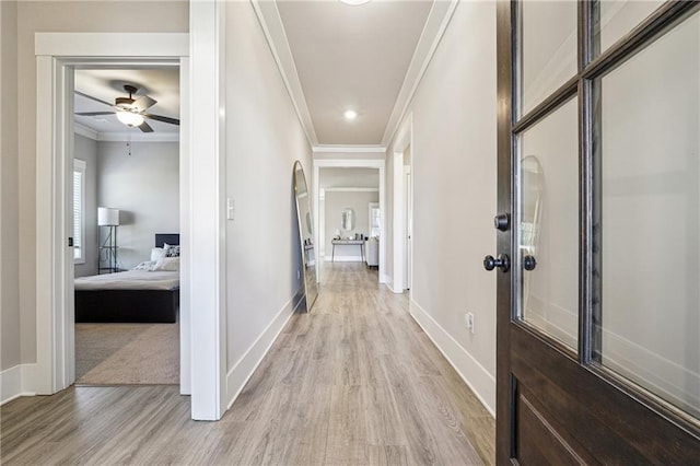 corridor with ornamental molding and light hardwood / wood-style floors