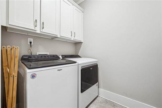 laundry area featuring cabinets, washing machine and dryer, and light tile patterned floors