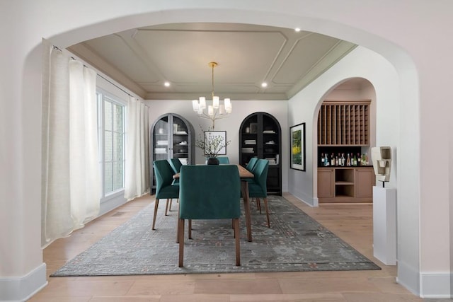 dining space featuring a tray ceiling, an inviting chandelier, and light hardwood / wood-style floors