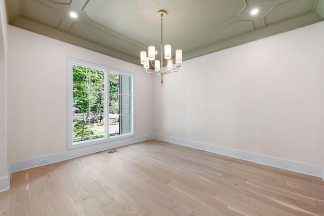 spare room featuring a notable chandelier and light hardwood / wood-style floors