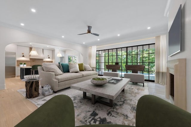 living room with crown molding, light hardwood / wood-style flooring, and ceiling fan