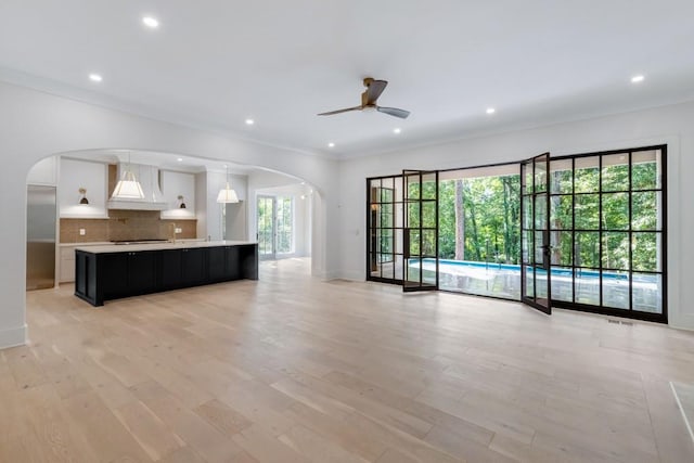 unfurnished living room with ceiling fan, light hardwood / wood-style floors, and crown molding