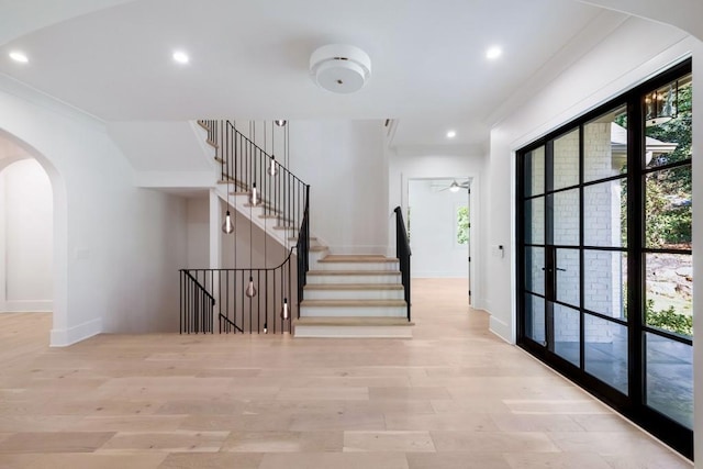 stairway featuring crown molding, wood-type flooring, and ceiling fan