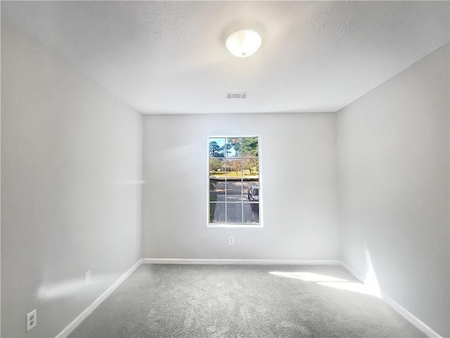 spare room with a textured ceiling and carpet