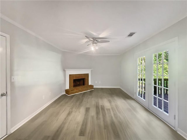 unfurnished living room featuring ornamental molding, hardwood / wood-style floors, a brick fireplace, and ceiling fan