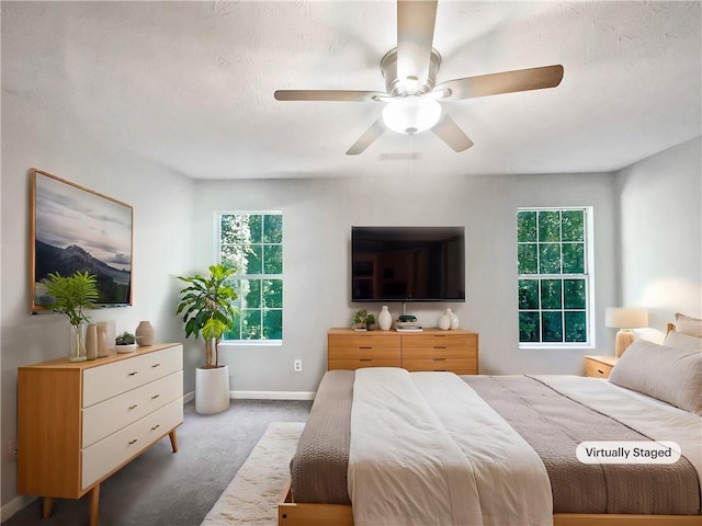 bedroom featuring ceiling fan, multiple windows, and carpet floors