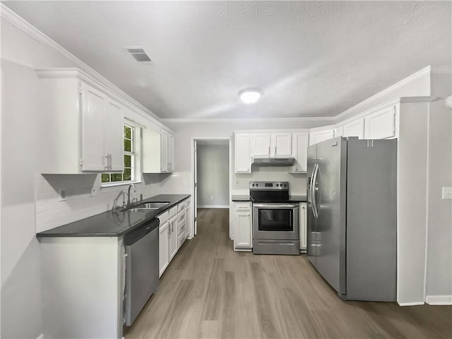 kitchen with appliances with stainless steel finishes, white cabinetry, sink, and hardwood / wood-style floors