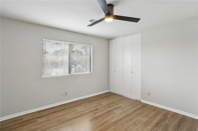 unfurnished bedroom featuring wood-type flooring, a closet, and ceiling fan