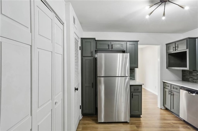 kitchen featuring appliances with stainless steel finishes, hardwood / wood-style floors, decorative backsplash, and gray cabinetry