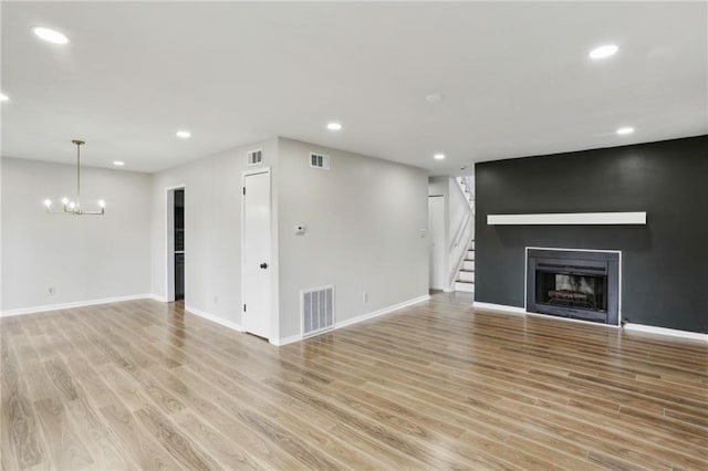 unfurnished living room with a notable chandelier and light hardwood / wood-style flooring