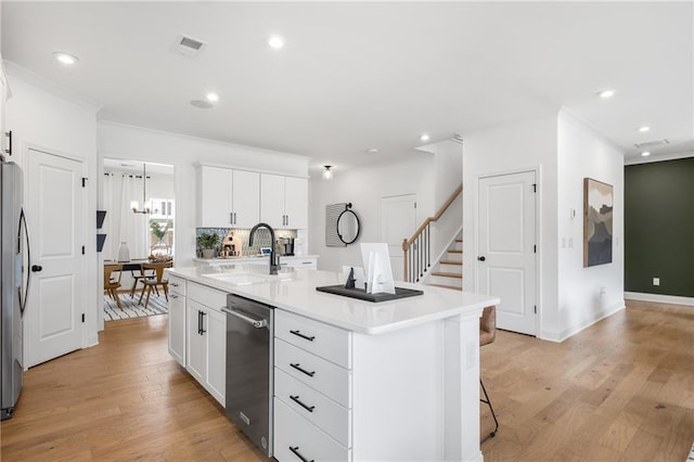 kitchen with a kitchen island with sink, appliances with stainless steel finishes, light wood-type flooring, sink, and white cabinetry