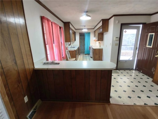 kitchen featuring sink, crown molding, light hardwood / wood-style floors, and kitchen peninsula