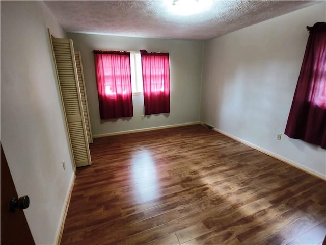 empty room featuring dark hardwood / wood-style flooring and a textured ceiling