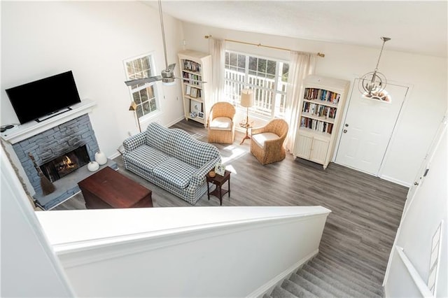 living room with a stone fireplace, dark wood-type flooring, and a notable chandelier