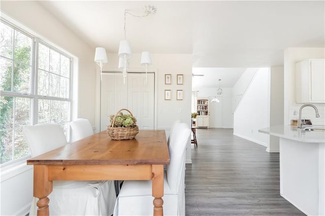 dining space with dark hardwood / wood-style flooring, sink, and a notable chandelier