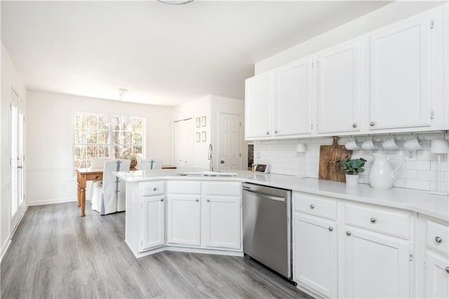 kitchen featuring pendant lighting, sink, stainless steel dishwasher, decorative backsplash, and white cabinetry