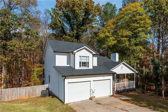 exterior space featuring central AC unit, covered porch, a front yard, and a garage