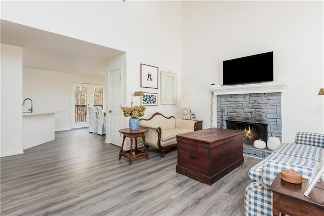 living room with a stone fireplace, sink, and light wood-type flooring