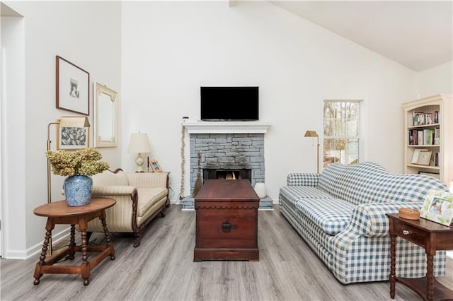 living room with a fireplace, light hardwood / wood-style flooring, and high vaulted ceiling