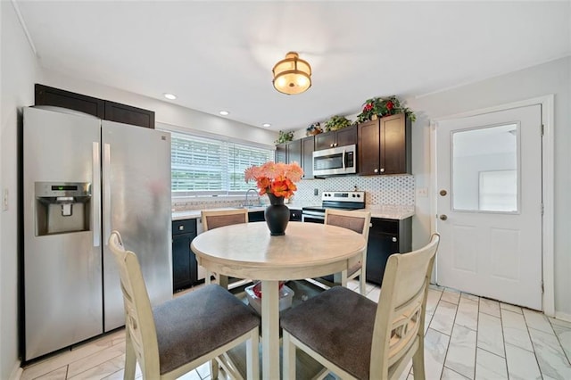 kitchen with stainless steel appliances, tasteful backsplash, light countertops, a sink, and dark brown cabinets