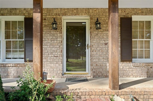 property entrance with covered porch and brick siding