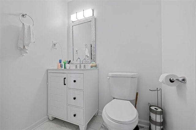 half bath featuring toilet, marble finish floor, baseboards, and vanity