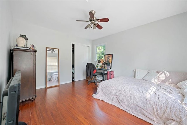 bedroom with a ceiling fan, baseboards, dark wood finished floors, and a closet