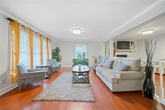 living room with baseboards, a fireplace, ornamental molding, and wood finished floors