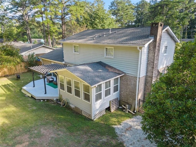 back of house featuring roof with shingles, brick siding, a chimney, a lawn, and a deck